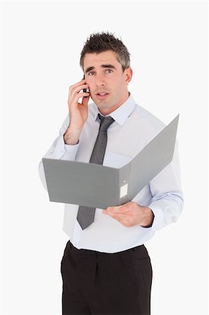 simsearch:400-06393704,k - Portrait of a man making a phone call while holding a binder against a white background Stockbilder - Microstock & Abonnement, Bildnummer: 400-05353960