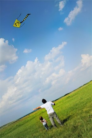 family outdoors and bright sun - Little girl and her father with flying a kite in the summer field Stock Photo - Budget Royalty-Free & Subscription, Code: 400-05365284