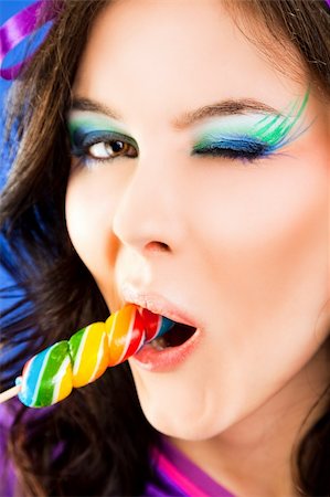 Close-up of beautiful female face giving a blink, biting lollipop Stock Photo - Budget Royalty-Free & Subscription, Code: 400-05360401