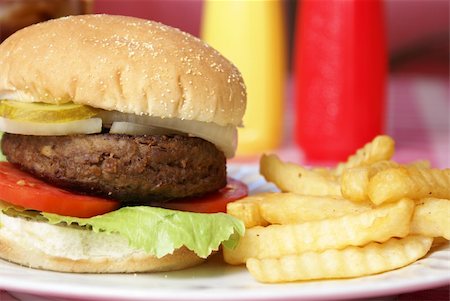 plate of hamburger and fries - A freshly served hamburger meal on a table with condiments in the background. Stock Photo - Budget Royalty-Free & Subscription, Code: 400-05361546