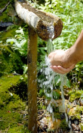fresh spring drinking water - man washing his hands by spring water under wooden gutter over green natural background Stock Photo - Budget Royalty-Free & Subscription, Code: 400-05362952