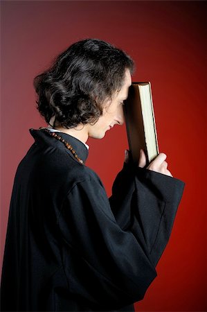 simsearch:400-06794896,k - conceptual portrait of Praying priest with wooden cross reading Holy Bible. red background Stock Photo - Budget Royalty-Free & Subscription, Code: 400-05379367