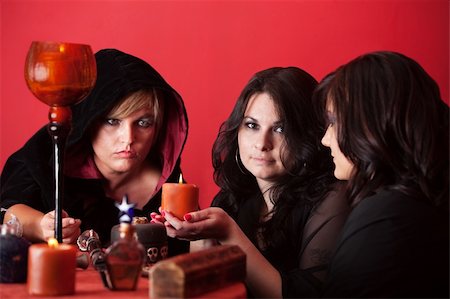 simsearch:400-05347613,k - Woman holds candle while two other witches watch over red background Stock Photo - Budget Royalty-Free & Subscription, Code: 400-05379705