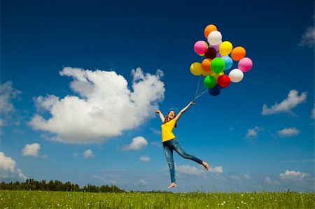 simsearch:400-06077546,k - Happy young woman holding colorful balloons and flying over a green meadow Stockbilder - Microstock & Abonnement, Bildnummer: 400-05385595