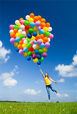simsearch:400-06077546,k - Happy young woman holding colorful balloons and flying over a green meadow Stockbilder - Microstock & Abonnement, Bildnummer: 400-05385597