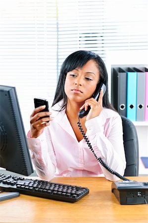 female manager talking to concerned employee - Young black business woman multitasking using two phones in office Stock Photo - Budget Royalty-Free & Subscription, Code: 400-05386063