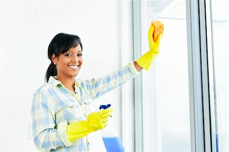 simsearch:700-01083983,k - Smiling black woman cleaning windows with glass cleaner Stock Photo - Budget Royalty-Free & Subscription, Code: 400-05380225