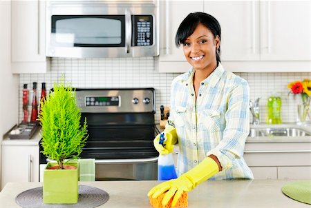 simsearch:600-02593992,k - Smiling young black woman with sponge and rubber gloves cleaning kitchen Photographie de stock - Aubaine LD & Abonnement, Code: 400-05380298