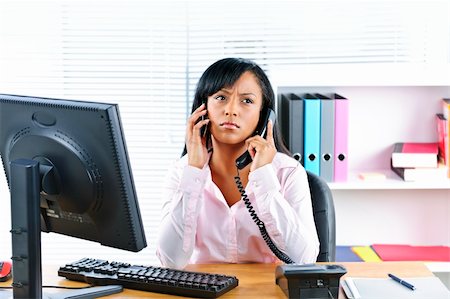 female manager talking to concerned employee - Young black business woman multitasking using two phones in office Stock Photo - Budget Royalty-Free & Subscription, Code: 400-05380310