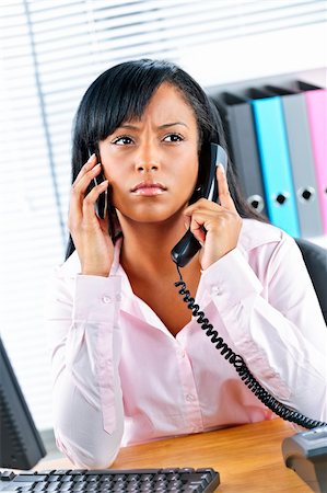 female manager talking to concerned employee - Young black business woman multitasking using two phones in office Stock Photo - Budget Royalty-Free & Subscription, Code: 400-05380312