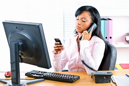 female manager talking to concerned employee - Young black business woman multitasking using two phones in office Stock Photo - Budget Royalty-Free & Subscription, Code: 400-05380313
