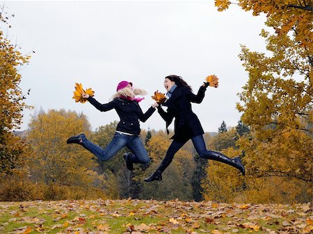 two beautiful girl friends with autumn leafs in a park jumping Stock Photo - Budget Royalty-Free & Subscription, Code: 400-05669098