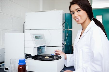 Female scientist using a centrifuge while looking at the camera Fotografie stock - Microstock e Abbonamento, Codice: 400-05669743