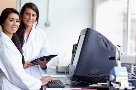 scientist pointing image - Smiling female scientist posing with a monitor while looking at the camera Stock Photo - Budget Royalty-Free & Subscription, Code: 400-05669769