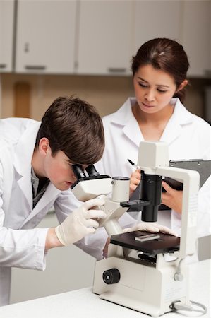 simsearch:400-05670478,k - Portrait of a scientist looking in a microscope while his colleague is taking notes in a laboratory Stock Photo - Budget Royalty-Free & Subscription, Code: 400-05669957