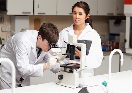 simsearch:400-05670478,k - Portrait of a scientist looking in a microscope while his colleague is posing in a library Stock Photo - Budget Royalty-Free & Subscription, Code: 400-05669962