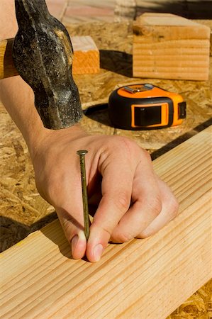 Construction worker hammering a nail into a piece of wood. Photographie de stock - Aubaine LD & Abonnement, Code: 400-05674376