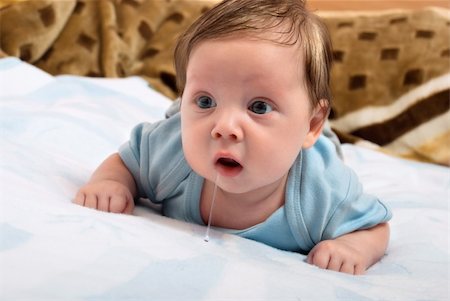 simsearch:400-04787509,k - Cute little baby looks into the camera and drooling while lying on the bed. Creative concept photos Photographie de stock - Aubaine LD & Abonnement, Code: 400-05675065