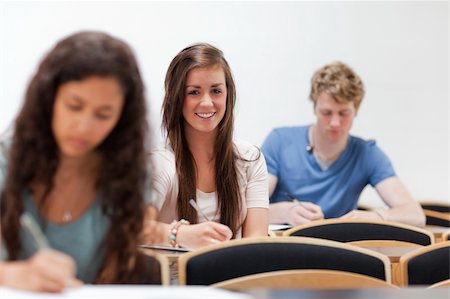 simsearch:400-05684337,k - Smiling young students sitting on a chair in an amphitheater Foto de stock - Royalty-Free Super Valor e Assinatura, Número: 400-05677818