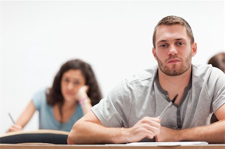 simsearch:400-05684337,k - Smiling handsome student sitting in an amphitheater Foto de stock - Royalty-Free Super Valor e Assinatura, Número: 400-05677828