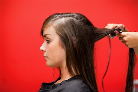raddrizzare - Woman having her hair straightened against a red background Fotografie stock - Microstock e Abbonamento, Codice: 400-05677974