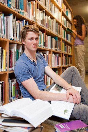 picking up books - Portrait of a male student with books while his classmate is reading in a library Stock Photo - Budget Royalty-Free & Subscription, Code: 400-05678077