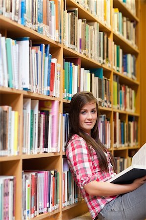 simsearch:400-05678140,k - Portrait of a young female student holding a book in a library Stockbilder - Microstock & Abonnement, Bildnummer: 400-05678114