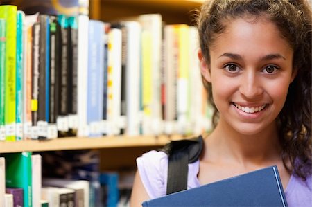 simsearch:400-05678140,k - Happy female student holding a book in a library Stockbilder - Microstock & Abonnement, Bildnummer: 400-05678138