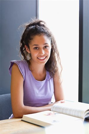 simsearch:400-05678093,k - Portrait of a smiling student sitting with a book in a library Stock Photo - Budget Royalty-Free & Subscription, Code: 400-05678145