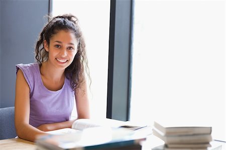 simsearch:400-05678093,k - Smiling student sitting with a book in a library Stock Photo - Budget Royalty-Free & Subscription, Code: 400-05678146