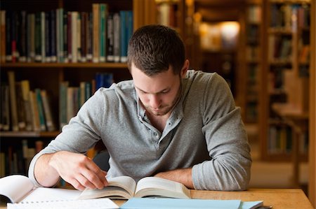 simsearch:400-05678093,k - Male student researching with a book in a library Stock Photo - Budget Royalty-Free & Subscription, Code: 400-05678143