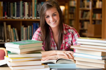 simsearch:400-05669803,k - Smiling student having a lot to read in a library Photographie de stock - Aubaine LD & Abonnement, Code: 400-05678155