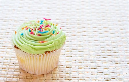 simsearch:400-05316582,k - Fresh vanilla cupcake with lime icing on woven straw background Stock Photo - Budget Royalty-Free & Subscription, Code: 400-05678329