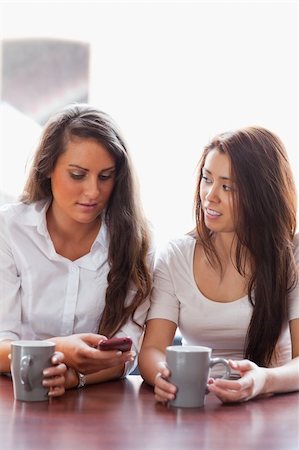 Portrait of friends looking at a smartphone while having a coffee Stock Photo - Budget Royalty-Free & Subscription, Code: 400-05670057
