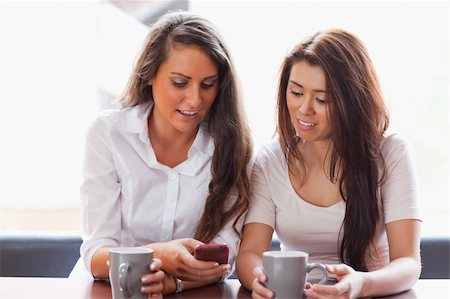 Friends looking at a smartphone while having a coffee Stock Photo - Budget Royalty-Free & Subscription, Code: 400-05670053