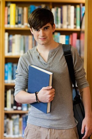 simsearch:400-05669803,k - Young student holding a book in the library Photographie de stock - Aubaine LD & Abonnement, Code: 400-05670288