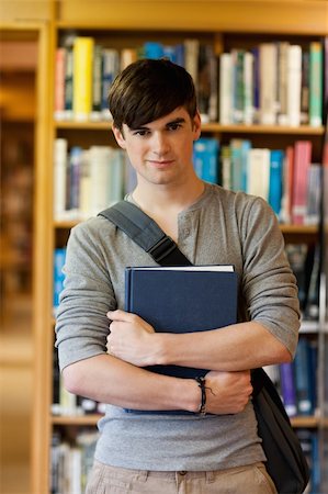 simsearch:400-05669803,k - Portrait of young student holding a book in the library Photographie de stock - Aubaine LD & Abonnement, Code: 400-05670289