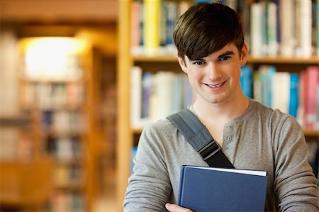 simsearch:400-05678140,k - Smiling young student holding a book in a library Stockbilder - Microstock & Abonnement, Bildnummer: 400-05670290