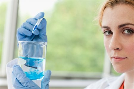 simsearch:400-05669818,k - Scientist dropping liquid in a beaker in a laboratory Fotografie stock - Microstock e Abbonamento, Codice: 400-05670582