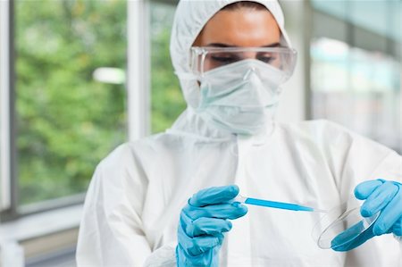 simsearch:400-05670362,k - Protected female science student dropping blue liquid in a Petri dish in a laboratory Stock Photo - Budget Royalty-Free & Subscription, Code: 400-05670592