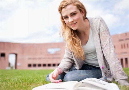 simsearch:400-04129453,k - Young woman posing with a book while sitting on the lawn Stock Photo - Budget Royalty-Free & Subscription, Code: 400-05670673