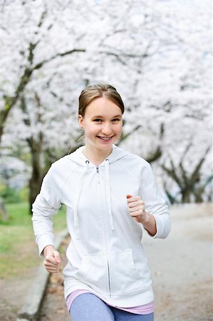 Beautiful teenage girl jogging in park with blooming apple trees Photographie de stock - Aubaine LD & Abonnement, Code: 400-05670768