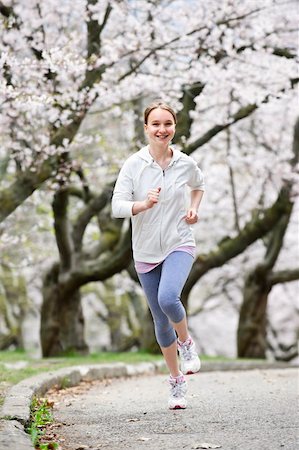 Beautiful teenage girl jogging in park with blooming apple trees Photographie de stock - Aubaine LD & Abonnement, Code: 400-05670769