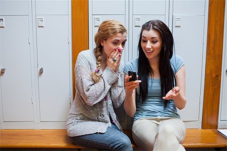 Surprised student showing a text message to her friend while sitting on a bench Stock Photo - Budget Royalty-Free & Subscription, Code: 400-05672288