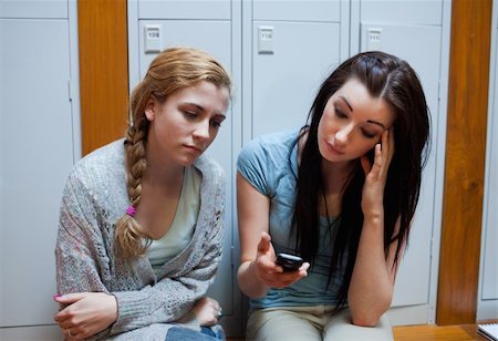 Sad student showing a text message to her friend while sitting on a bench Stock Photo - Budget Royalty-Free & Subscription, Code: 400-05672291