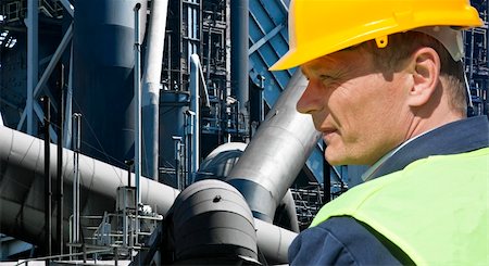 exhaust pipe - Stern looking worker in front of an imposing factory of a heavy industry facility Stock Photo - Budget Royalty-Free & Subscription, Code: 400-05686435