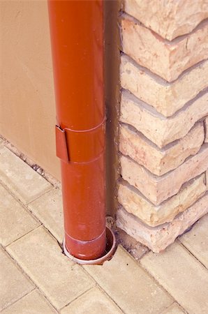 Red rainwater pipe made of tin on house corner made of decorative bricks. Fotografie stock - Microstock e Abbonamento, Codice: 400-05689275