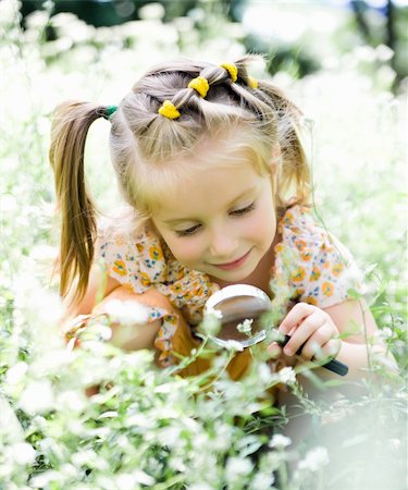 pretty little girl with magnifying glass looks at flower Stock Photo - Budget Royalty-Free & Subscription, Code: 400-05681683