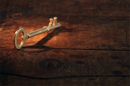 Closeup of vintage golden key standing on old wooden surface with beam of light Stock Photo - Budget Royalty-Free & Subscription, Code: 400-05683528