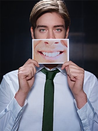 dental pictures black & white - young business man holding photo of toothy smile on black background. Vertical shape, front view, waist up Stock Photo - Budget Royalty-Free & Subscription, Code: 400-05696094